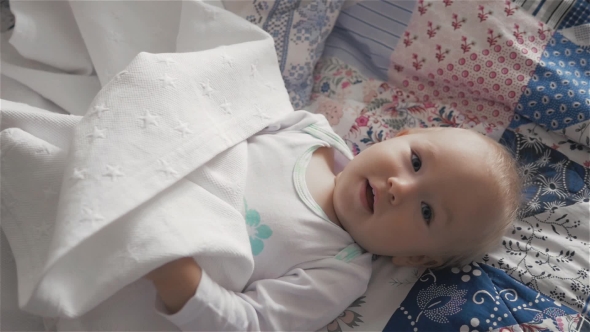 Little Cute Baby Girl On The Bed Hiding And Playing With Sheets alt