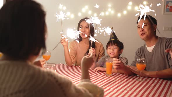 Asian big family enjoying birthday party with kid, They are playing sparkler with happiness together