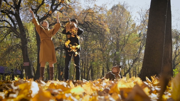 Happy Family Playing With Autumn Leaves In Park. Mom And Dad Throw Leas Up In The Air. Small Child