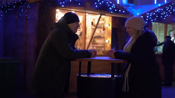 Happy Young Couple with Coffee at Christmas Market in Evening