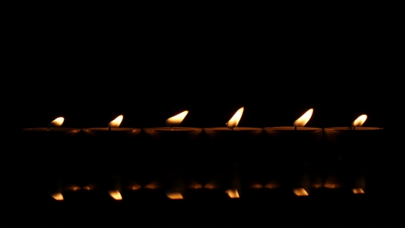 Six Candles On a Black Reflecting Background.