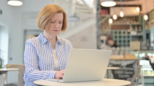 Laptop Use By Creative Old Woman in Cafe