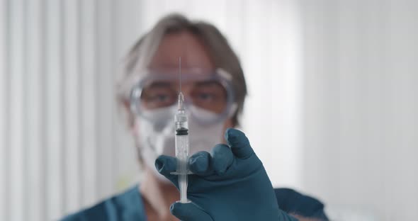 Middleaged Mature Physician Holding Syringe with Medicine