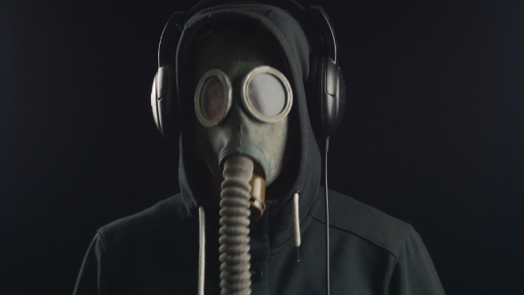 Man Listens To Music With Headphones And Dance With Gas Mask Covering His Face.