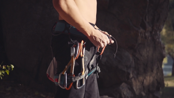 Topless Climber With Carabiners Dipping Hands In Chalk