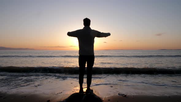 silhouette of man raising his hands in victory