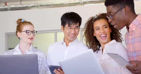 Multi-ethnic business people discussing over laptop and digital tablet in modern office 4k