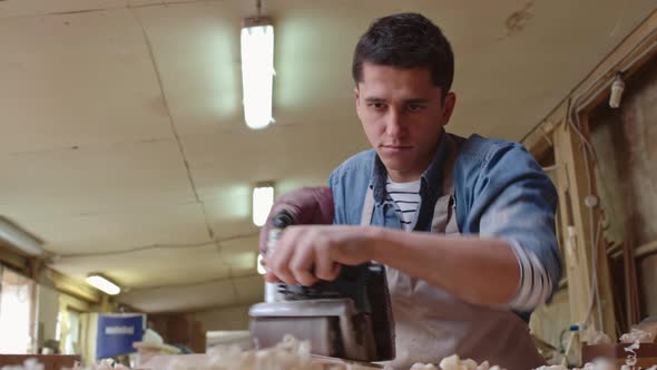 Carpenter Using Grinder on Wood Plank alt