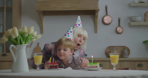 Cheerful Grandmother Celebrating Birthday with Grandson Together at Home. Family in Birthday Hats