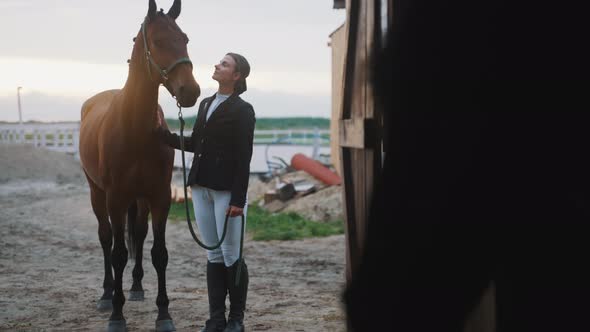 Horse Owner With Her Brown Horse Outside The Stable In The Sandy Ground