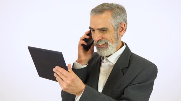 An Elderly Man Holds a Tablet and Talks on a Smartphone - White Screen Studio