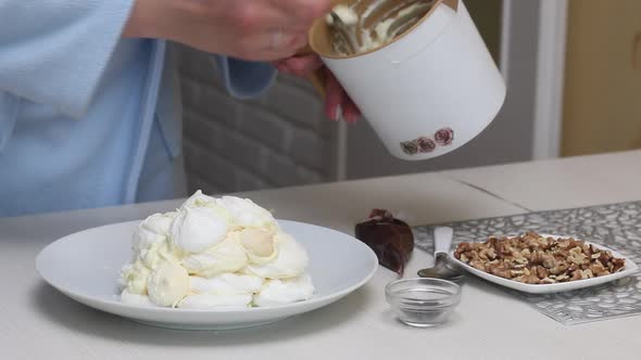 A Woman Prepares A Cake Count Ruins From Meringue. Coats Meringues With Cream, Stacked On A Plate