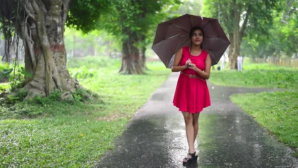 A pretty hot Caucasian girl enjoys the rainy season on road with her umbrella, Slow motion