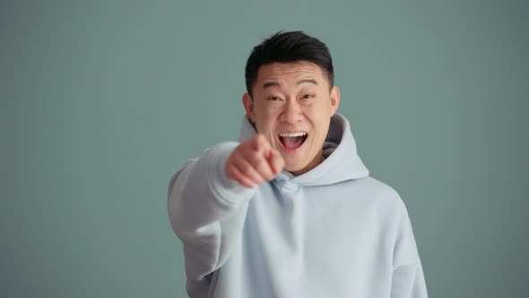 Smiling Asian man wearing hoodie pointing at the camera