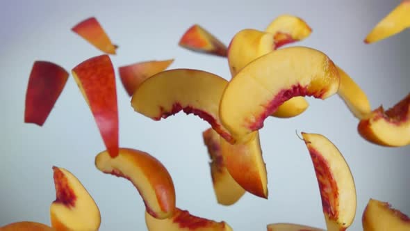 Slices of Peaches Bouncing and Rotating on White Background