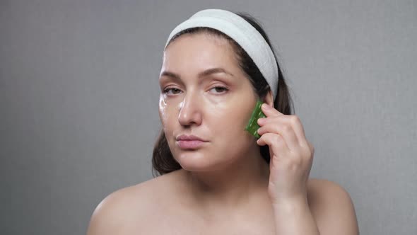 Woman Makes Facial Massage Using Juice of Cut Aloe Leaves