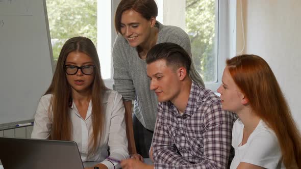 Young Woman Using Laptop, Working on a Project with Her Classmates 