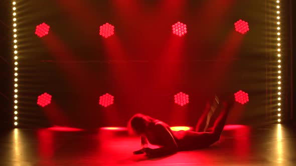 Brunette Young Women Dance Rhythmic Gymnastics. Silhouettes Against the Background of Red Spotlights