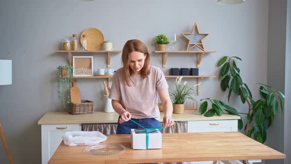 A Woman in the Kitchen Unpacks a Cake