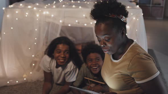 Mom Reading to Kids in Blanket Fort