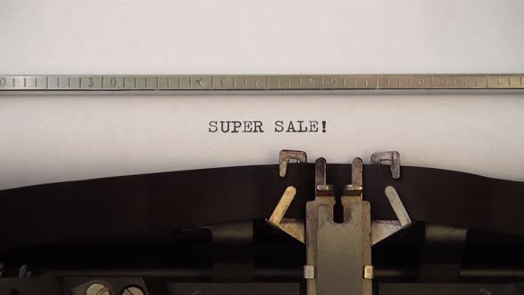 Typing phrase SUPER SALE ! on retro typewriter. Close up.