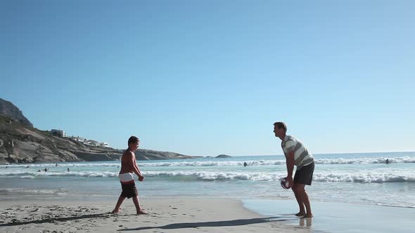 Father and son playing ball on beach