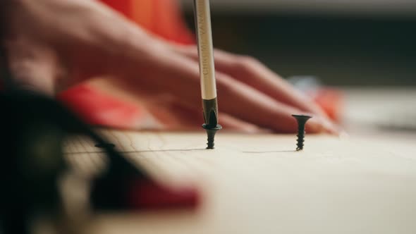 Woman Builder Tightening Screws with Manual Screwdriver Into Wooden Board Closeup