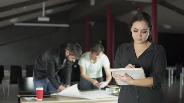 Portrait of a Fashionable Young Professional Woman Holding Folders with Papers and Taking Notes in a