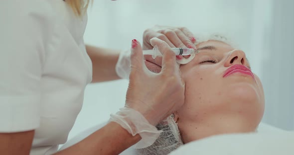Closeup of Beautician Hands Doing Facial Skin Lifting Injection to Young Woman Face