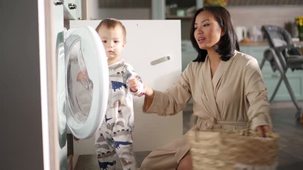 Lovely Asian mom and son put things in the washing machine