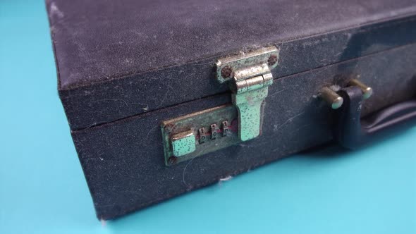 Person Presses Button To Open Old Dirty Case on Light Blue