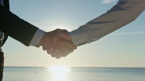 Entrepreneurs guys in classic suits shake hands.