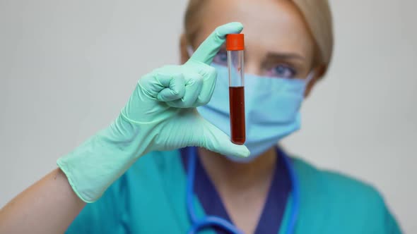 Medical Doctor Nurse Woman Wearing Protective Mask and Latex Gloves - Holding Blood Test Tube