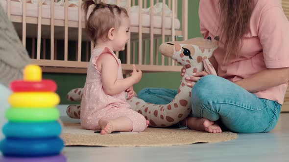 Mom and Baby Play Toys at Home While Sitting on the Floor in the Bedroom