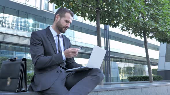 Businessman Doing Online Payment Via Laptop Outside Office