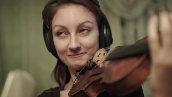 Female Violinist with Headphones Playing Violin at Microphone During a Rehearsal