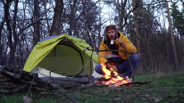 A Man Near a Campfire and a Tent in the Forest