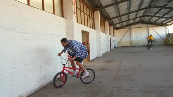 BMX riders in an empty warehouse