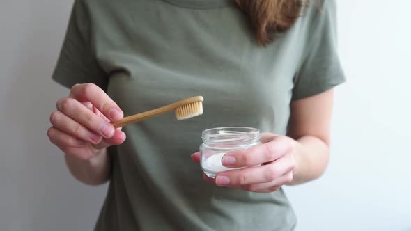 Woman Holds Bamboo Toothbrush and Soda Powder in Her Hands