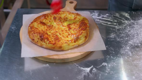 Closeup Smearing Cheese Pizza Using a Brush