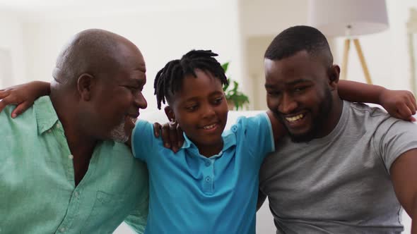 Portrait of african american grandfather, father and son smiling together at home