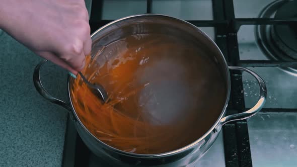 Female Hands Stir Spaghetti in a Saucepan with Boiling Water Slow Mo