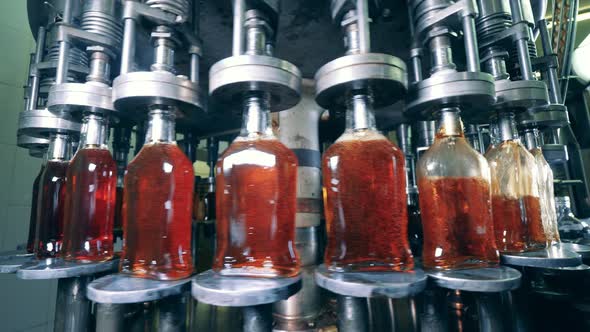 Glass Bottles in the Process of Getting Filled with Alcohol