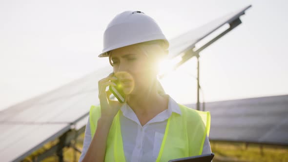 Close Up Portrait of Beautiful Female Technologist Talking on Mobile Phone Among Field of Solar