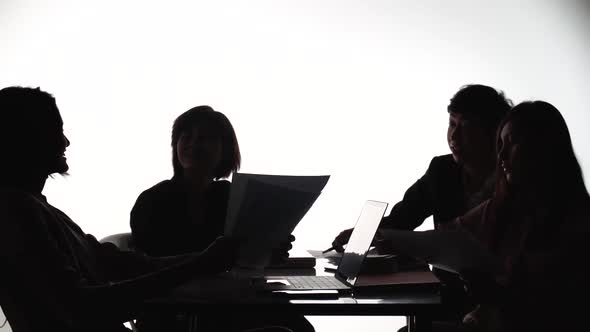 Silhouettes of people sitting at the table,Group of businesspeople high five together in a boardroom