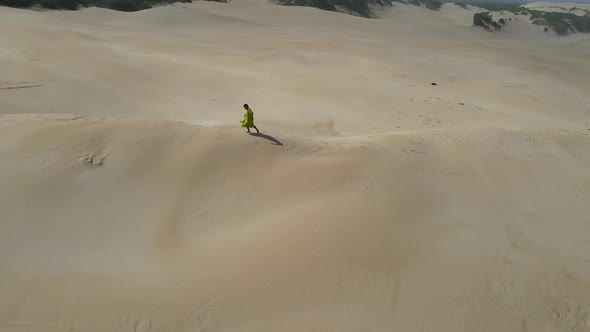 Aerial View of Woman Walking on Sand Dune