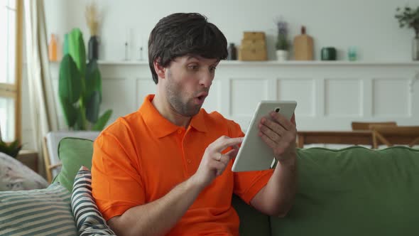 Overjoyed Man Sit Relax on Sofa Feel Euphoric Triumph Reading Good News on Modern Tablet