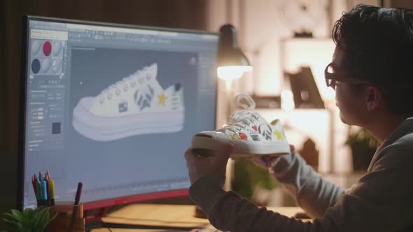 Close Up Of Asian Male Footwear Designer Looking At The Colourful Pattern Sneaker In Hands