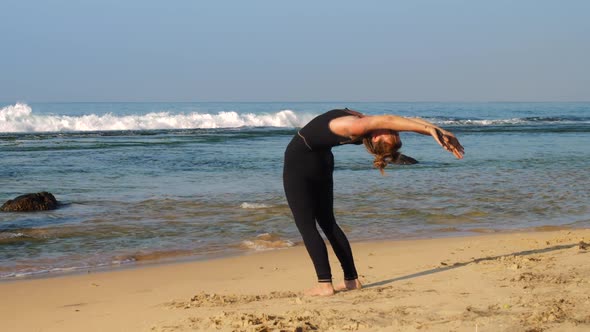 Sporty Lady Exercises on Sandy Beach at Waving Ocean