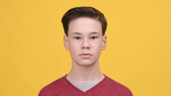 Portrait Of Serious Teenager Boy Posing Over Yellow Background